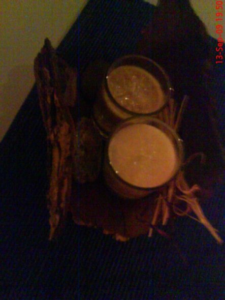 Ein Stück Baumrinde, 2 Gelkerzen in beige und creme, eine handvoll Flusskiesel und Sisalband.